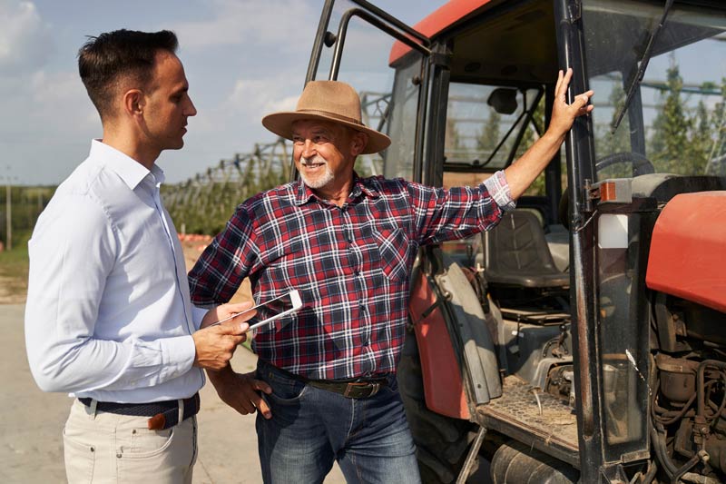 farmer and businessman standing next to tractor